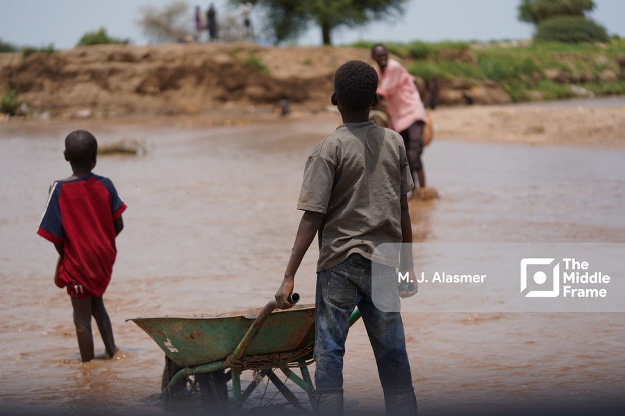 a boy carries a wheelbark in the river