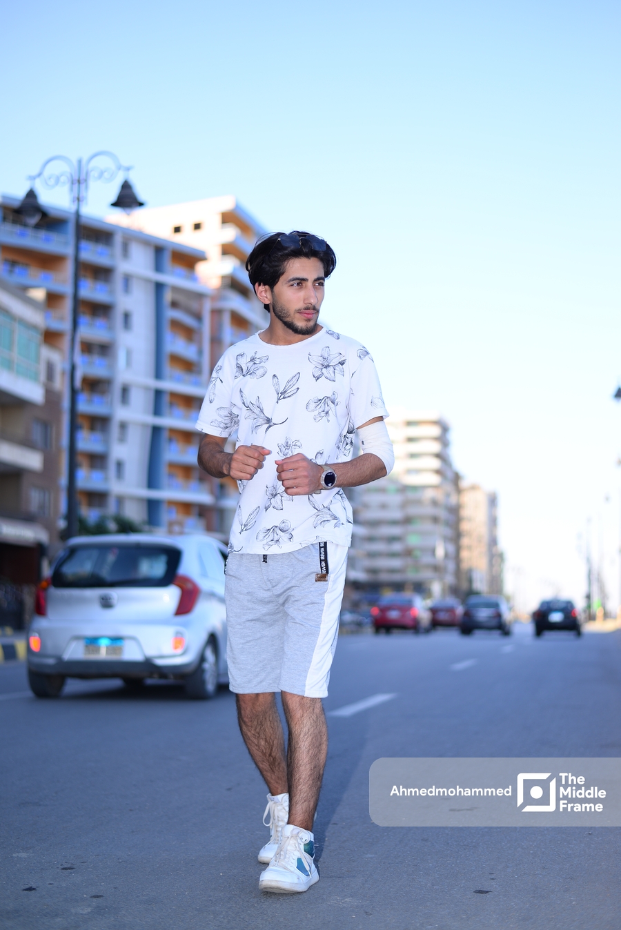 a man in a white shirt and shorts stands on the street