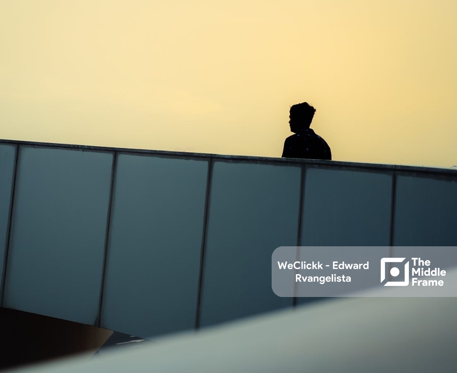 a man sitting on a roof looking out at the sunset.