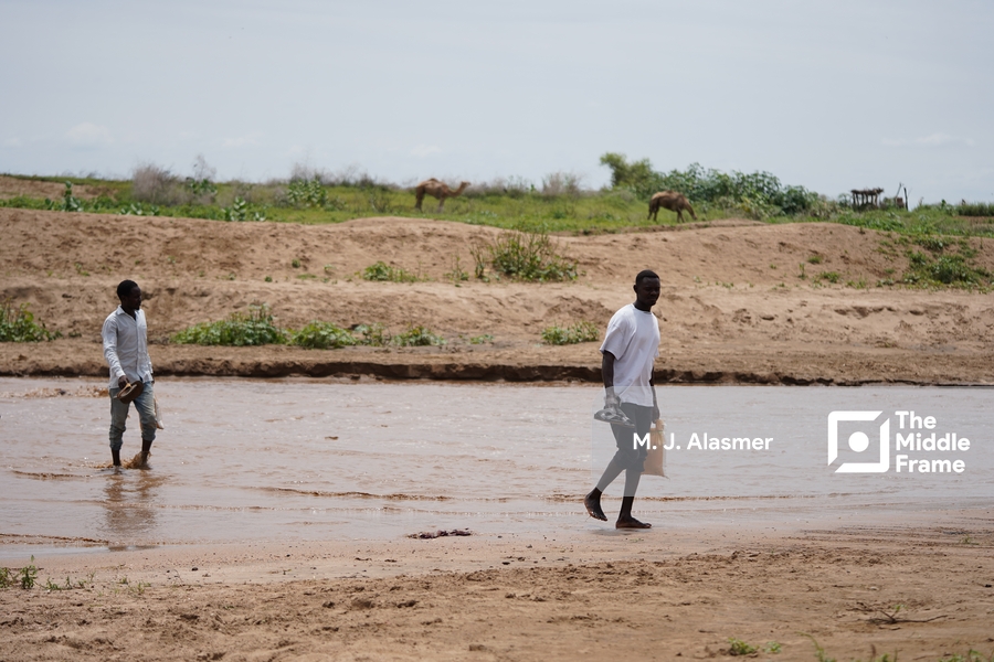 two men walking across a muddy river