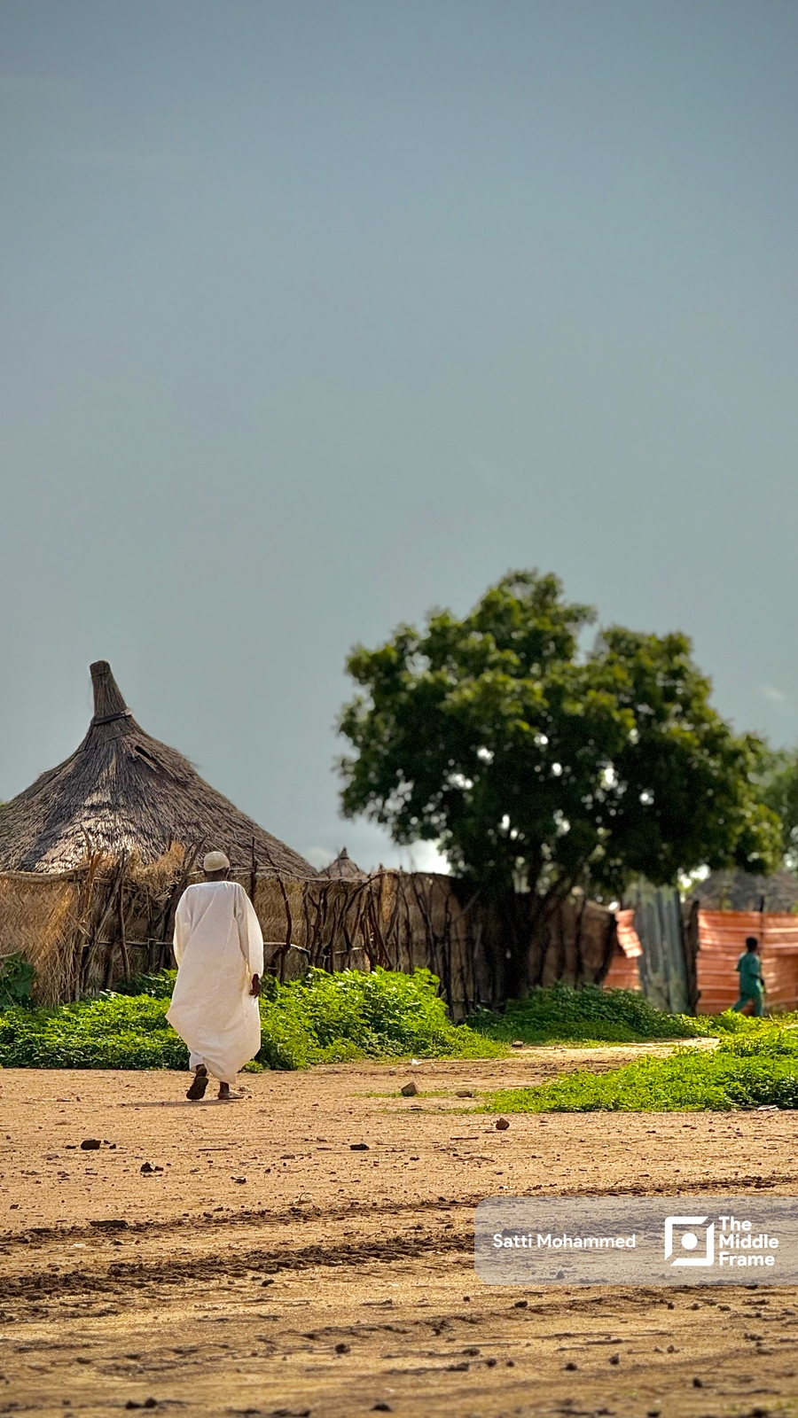 a man walking in front of a hut