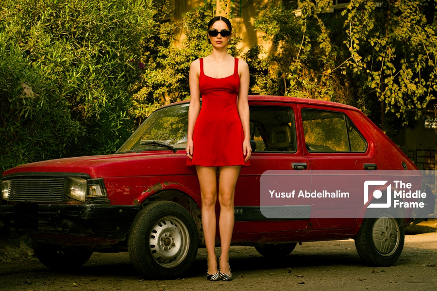 a woman in a red dress standing next to a red car