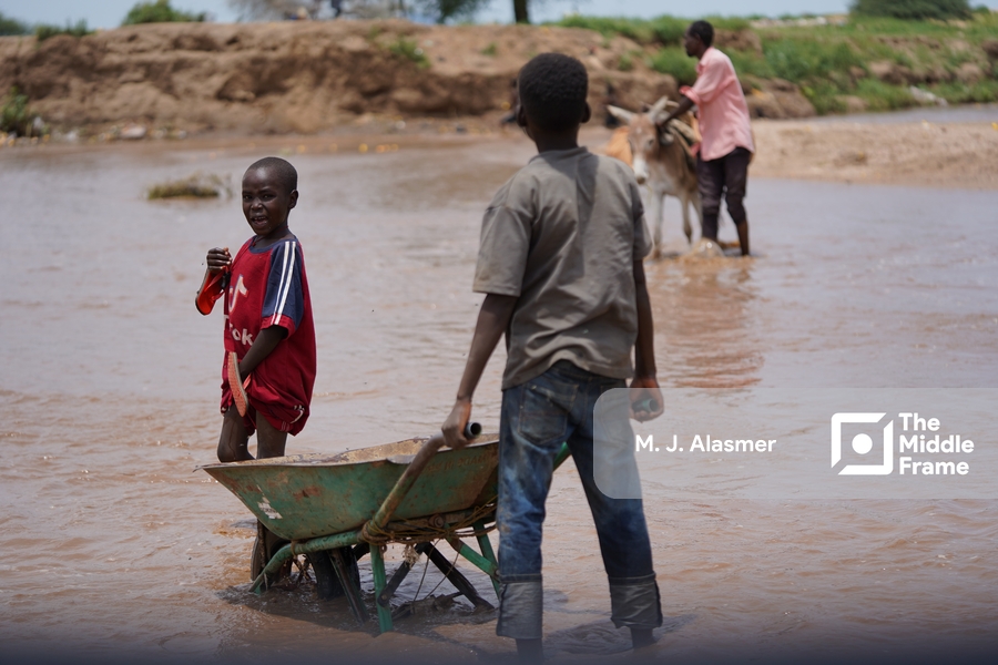 a boy is standing in the water with a wheel