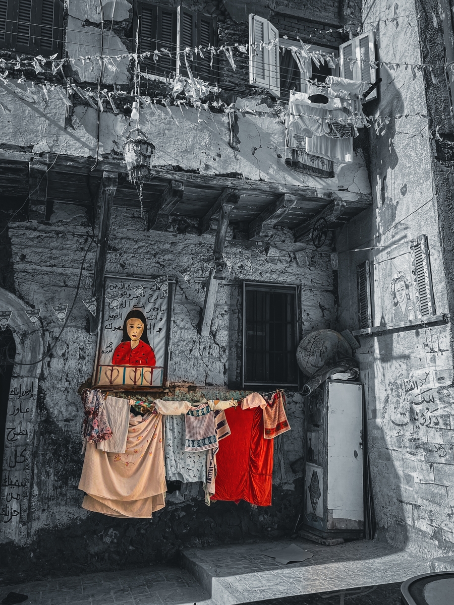 A drawing of a woman in a red dress stands in front of a destroyed building