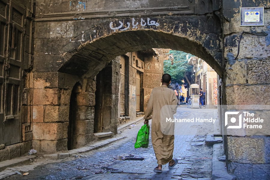 A man walking down a narrow street in old Cairo