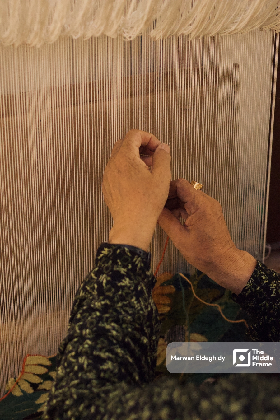 An old woman weaving a white fabric on