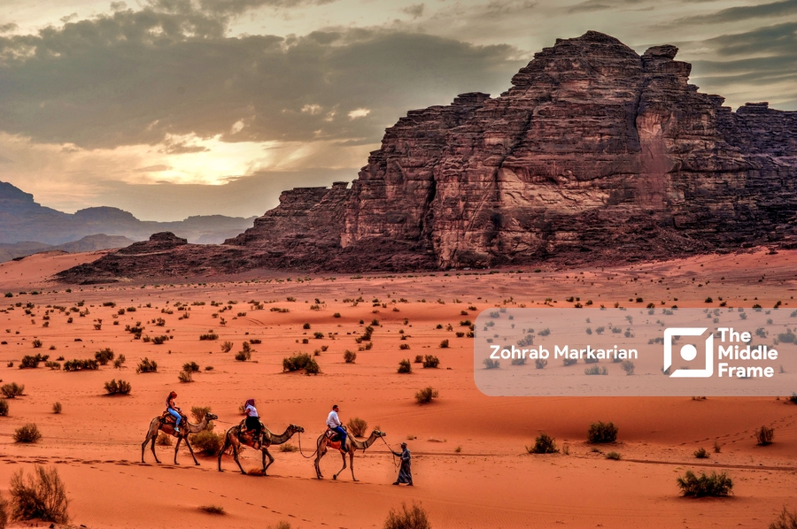 A group of people riding camels through the desert