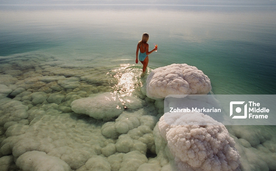A woman wearing a swimsuit standing on a rock in the water