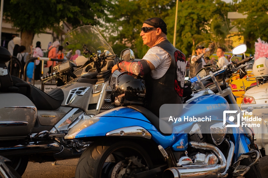 A biker sitting on his blue motorcycle.