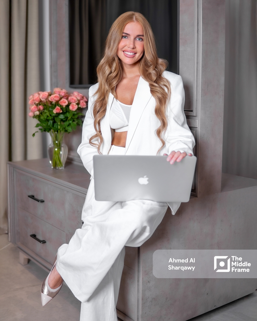 a woman sitting on a dressing table with a laptop wearing a business attire
