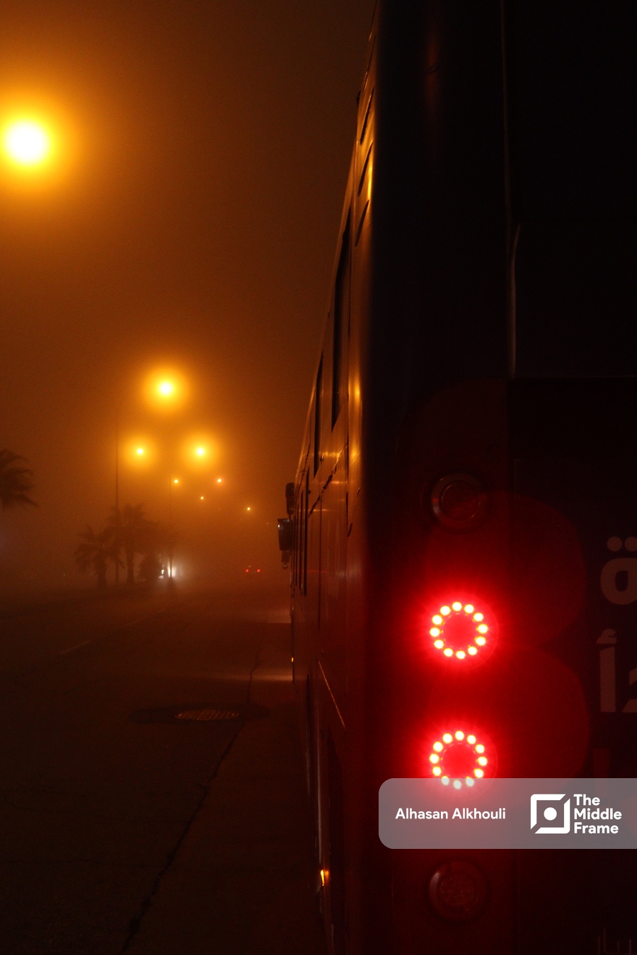 A bus is seen in the fog on a street