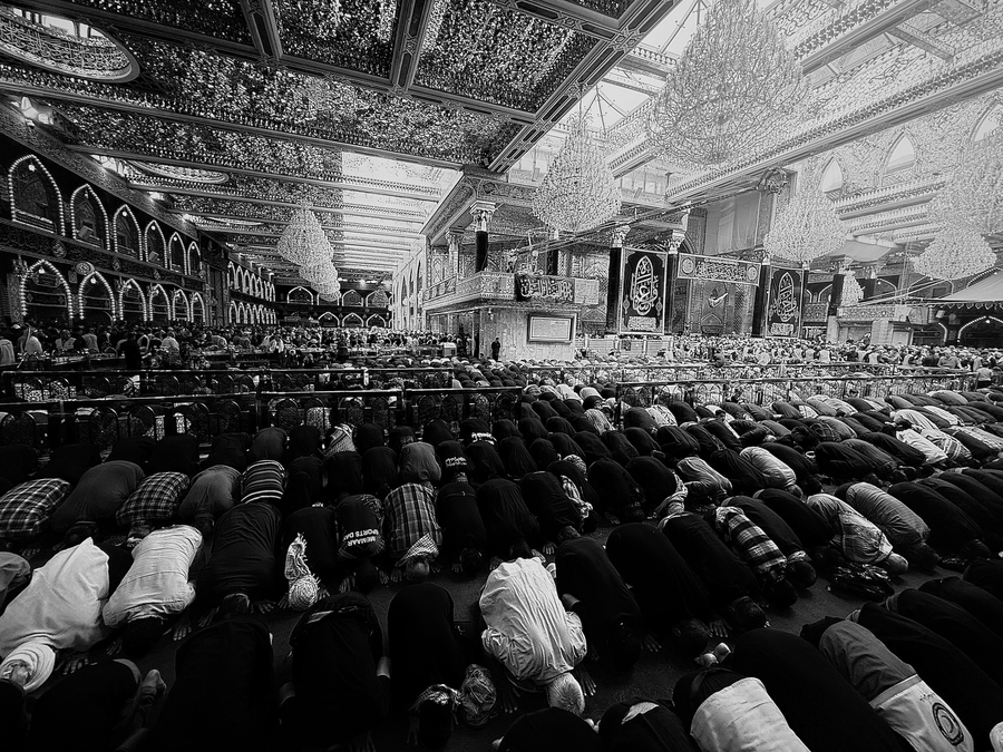 A large crowd of people are praying in a mosque