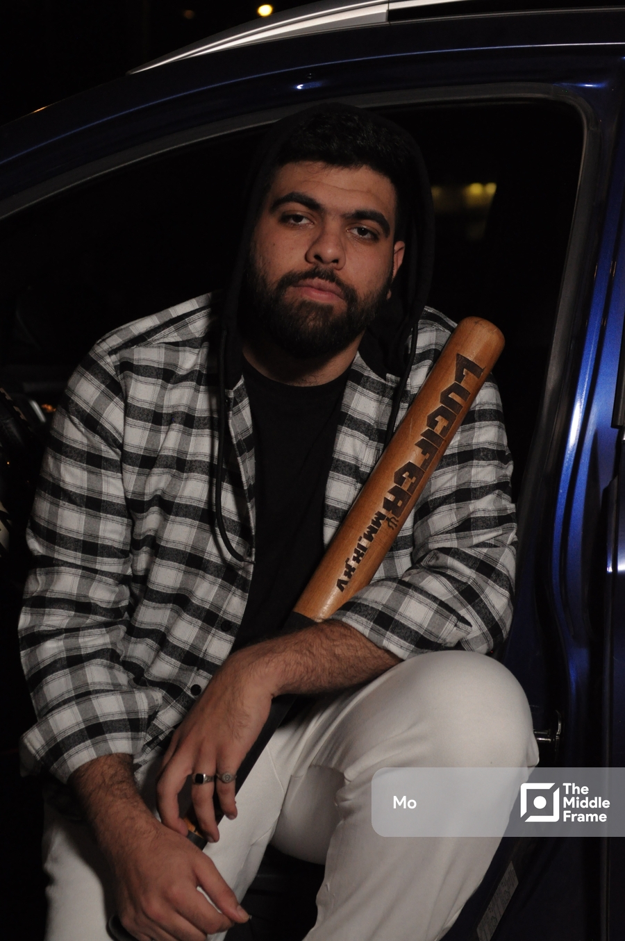a man sitting in the back of a car holding a bat