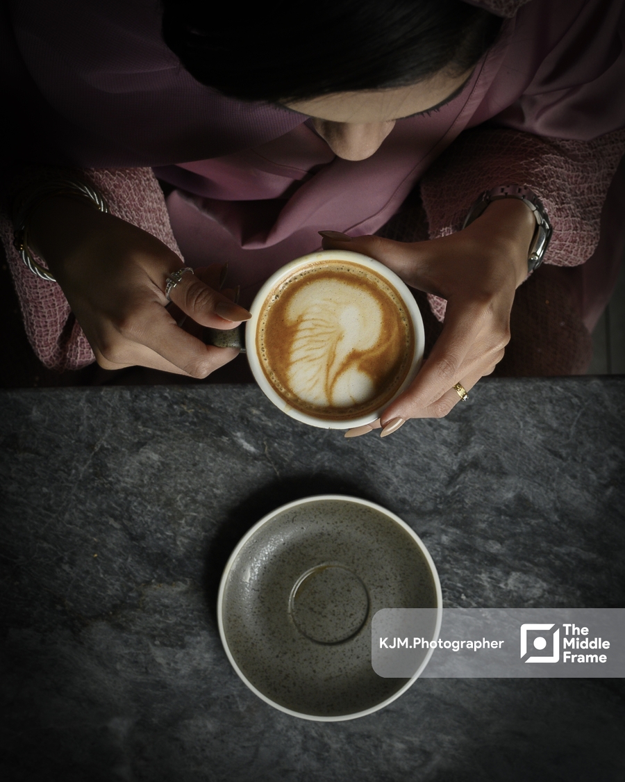 a woman sitting at a table with a cup of coffee