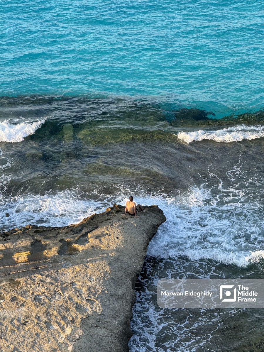 A man sitting on a rock in the ocean