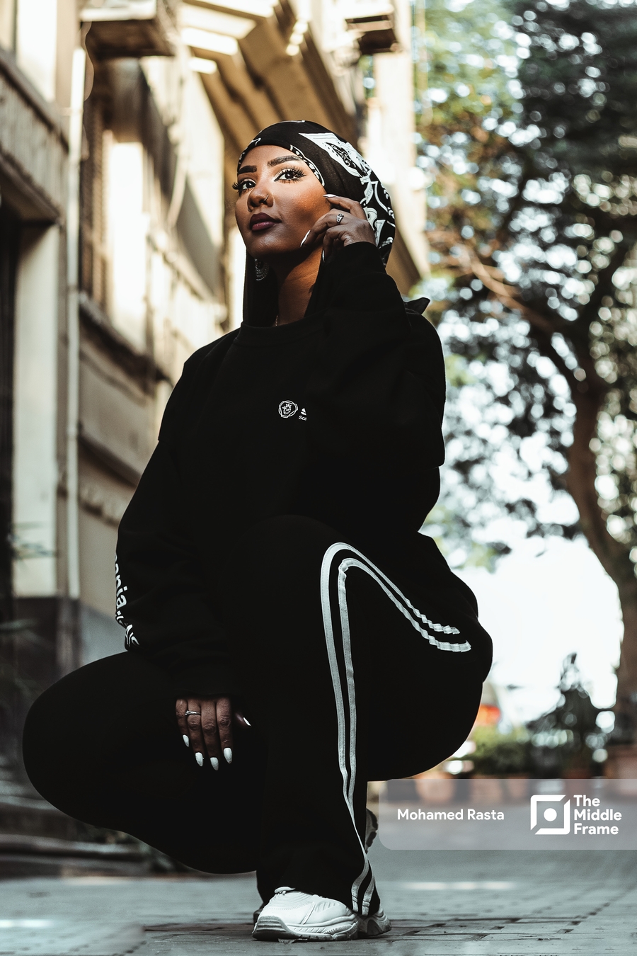 A young woman in a black outfit poses on the street in daylight in Egypt