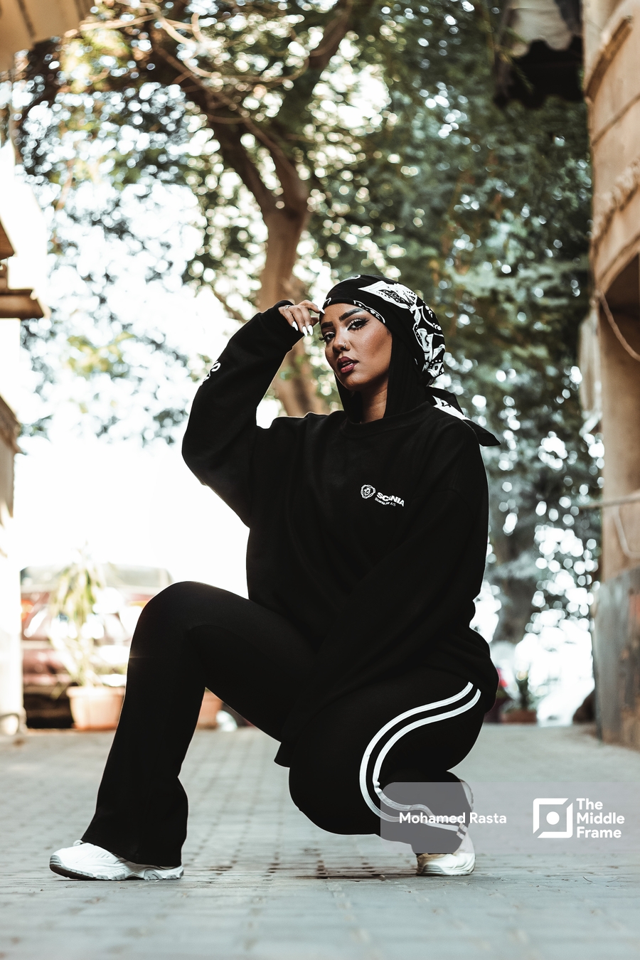 A young woman in a black outfit poses on the street in daylight in Egypt