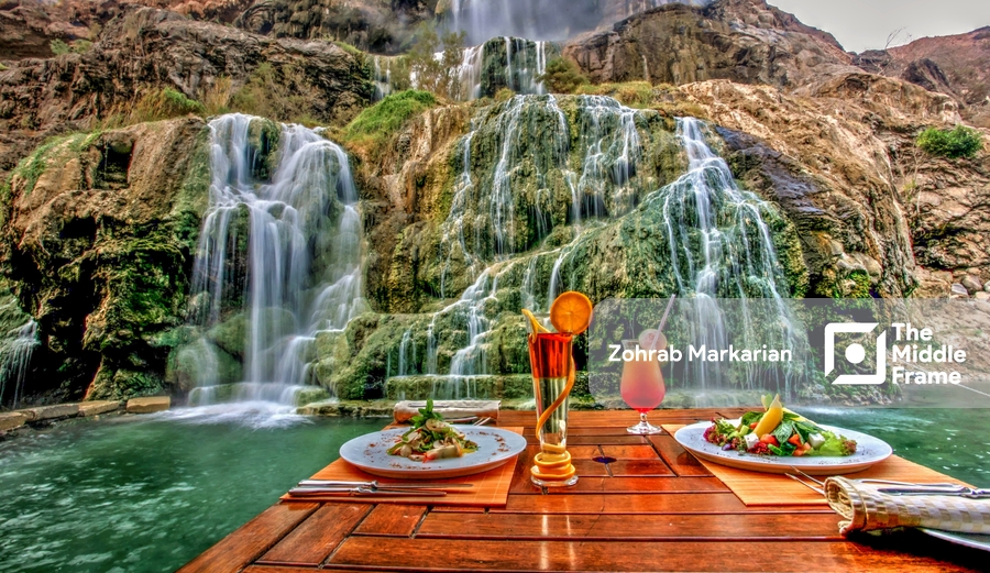 a table with plates of food and a waterfall in the background