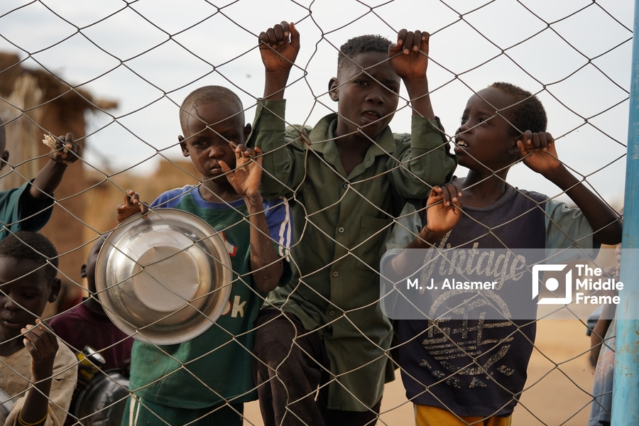 children stand behind a fence in a village