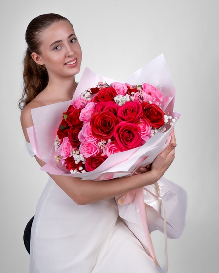 a beautiful young woman holding a bouquet of red roses