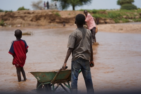 a boy carries a wheelbark in the river