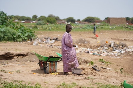 a woman in a purple dress is standing in the dirt
