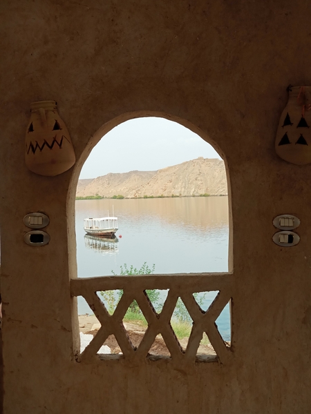 A view of a boat in the Nile river through an arched window in Egypt
