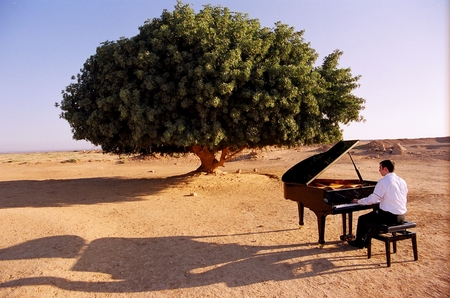 A man playing a piano in the desert
