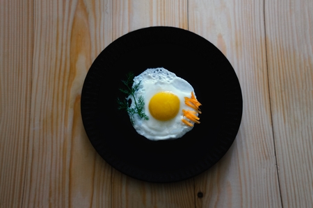 A fried egg on a black plate