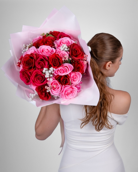 a woman holding a bouquet of pink and red roses