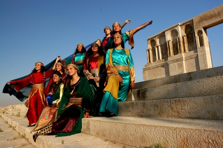 A group of young women in colorful dresses posing on steps