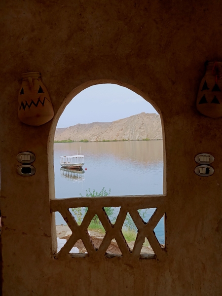 A view of a boat in the Nile river through an arched window in Egypt