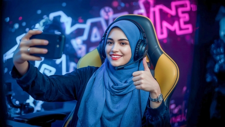 A woman wearing headphones and a scarf, sitting in front of a computer