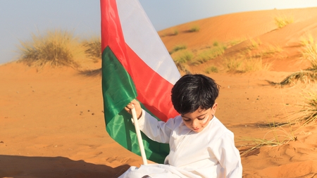 a boy in white clothes holding a flag