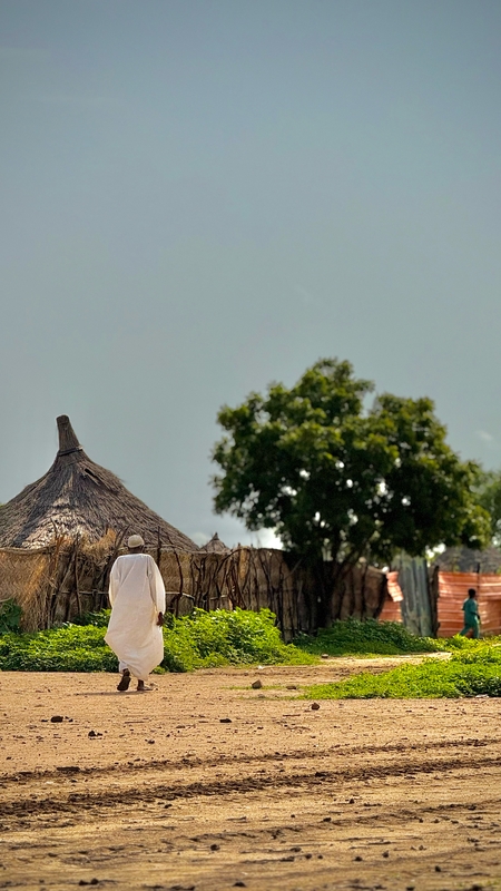 a man walking in front of a hut