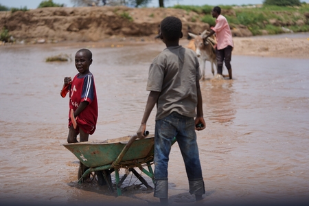 a boy is standing in the water with a wheel