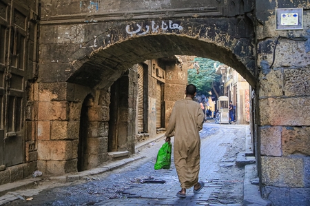 A man walking down a narrow street in old Cairo