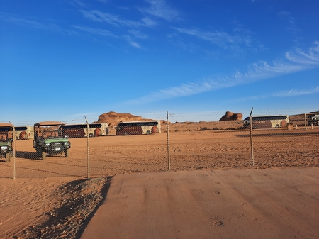 A dirt road with a fence and a building in the background