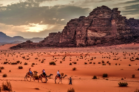 A group of people riding camels through the desert