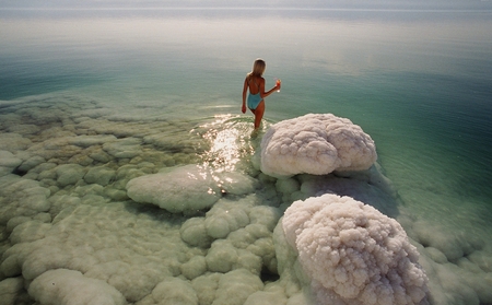 A woman wearing a swimsuit standing on a rock in the water