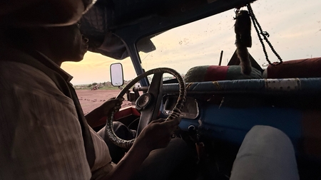 A man driving a car on a dirt road