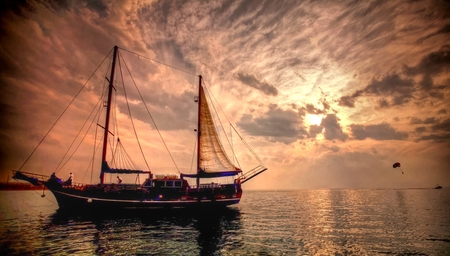 a sailer in the ocean at sunset