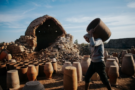The potter between the worn walls of the old kiln.