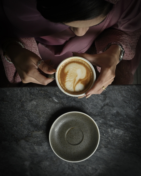 a woman sitting at a table with a cup of coffee