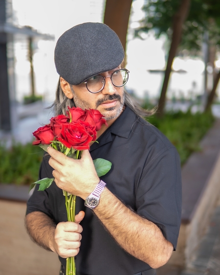a man with a beard and glasses holding a red rose