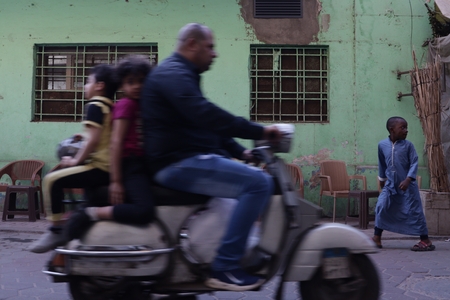 A man riding a vespa with his kids