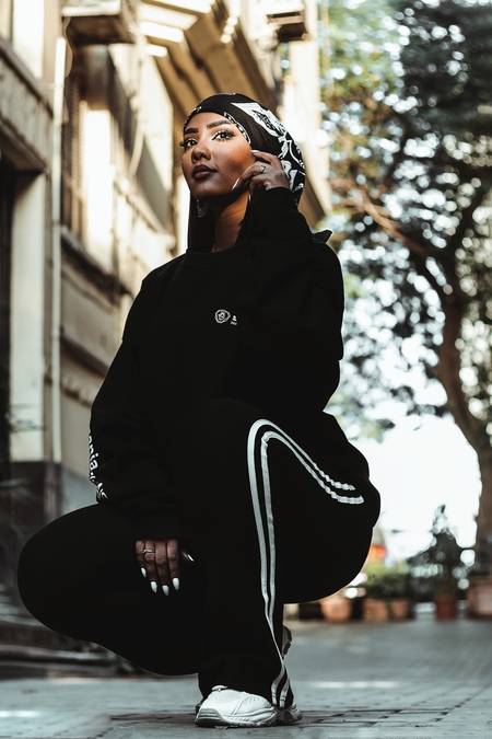 A young woman in a black outfit poses on the street in daylight in Egypt