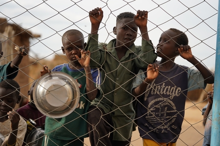children stand behind a fence in a village